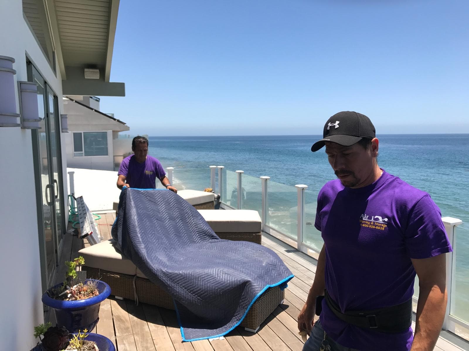 Air1 Moving professionals carefully moving furniture on oceanfront balcony